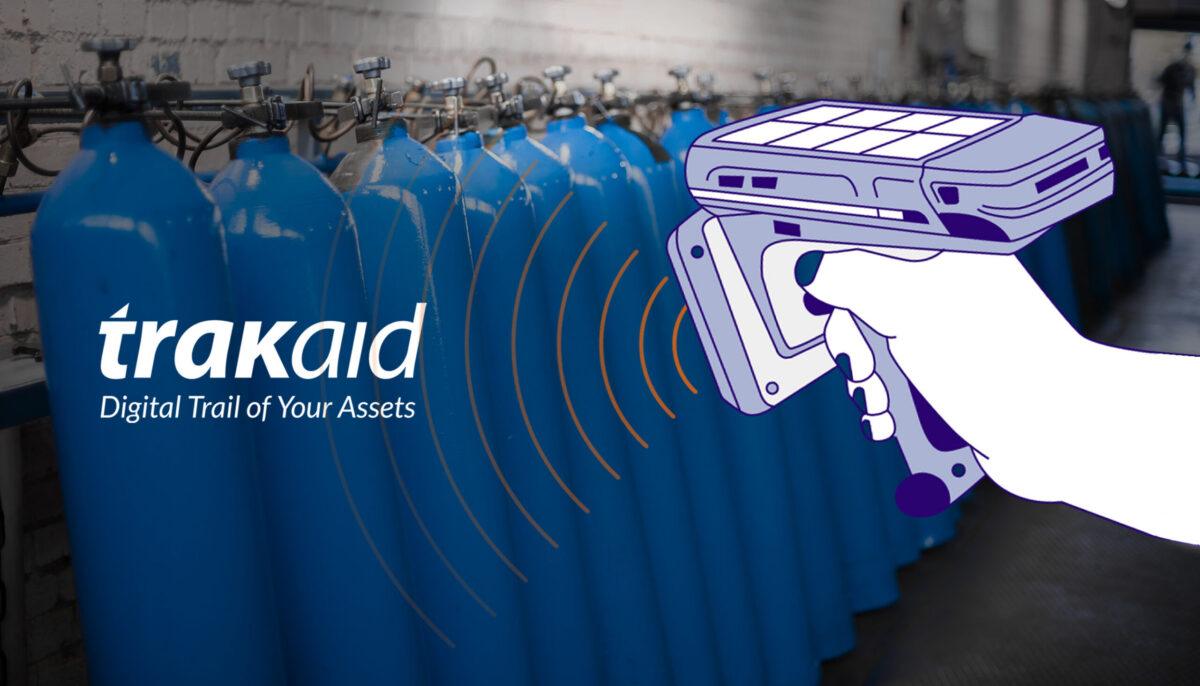 A hand is holding a card reader in front of a row of blue cylinders