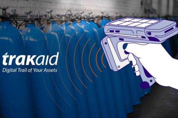 A hand is holding a card reader in front of a row of blue cylinders